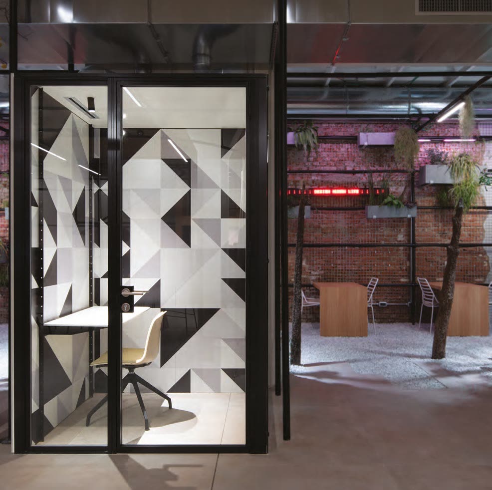 Phone booth clad in geometric black and white panels in a shared office