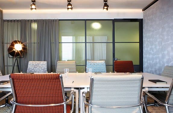 Meeting room behind black-framed glazing with statement lighting, Milan