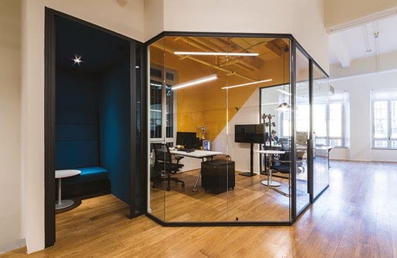 Black-framed glazed office with timber floor and an orange accent wall
