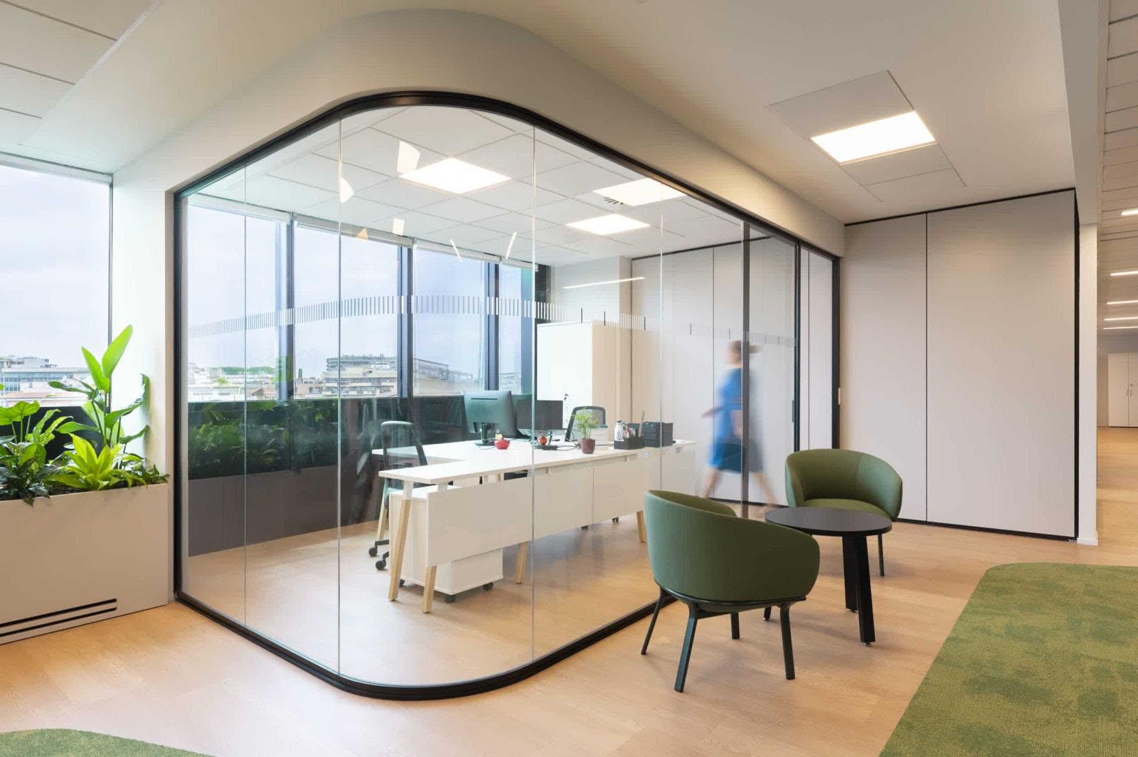 Glass office with curved corners on a planted office floor
