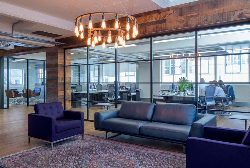 Warehouse-style black-grid glazing around a lounge with leather sofas, London