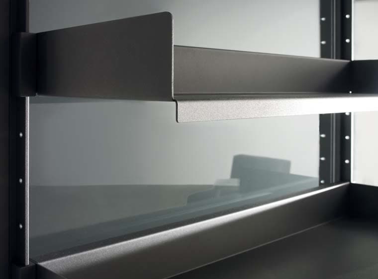 Detail of a shelf bracket hooked onto a partition upright behind the glass