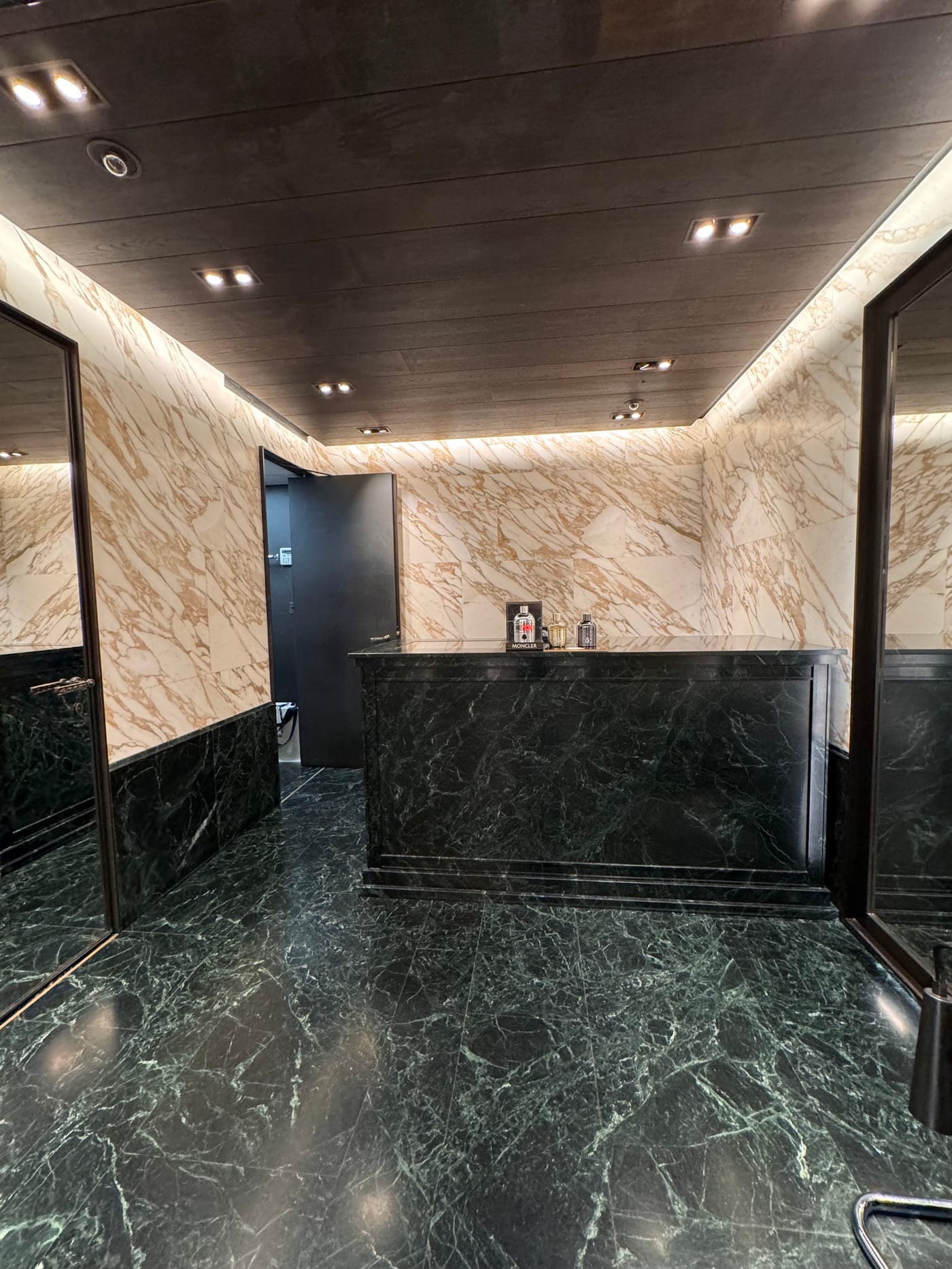 Service counter, green marble — Moncler · London · book-matched Calacatta cladding, slatted timber ceiling