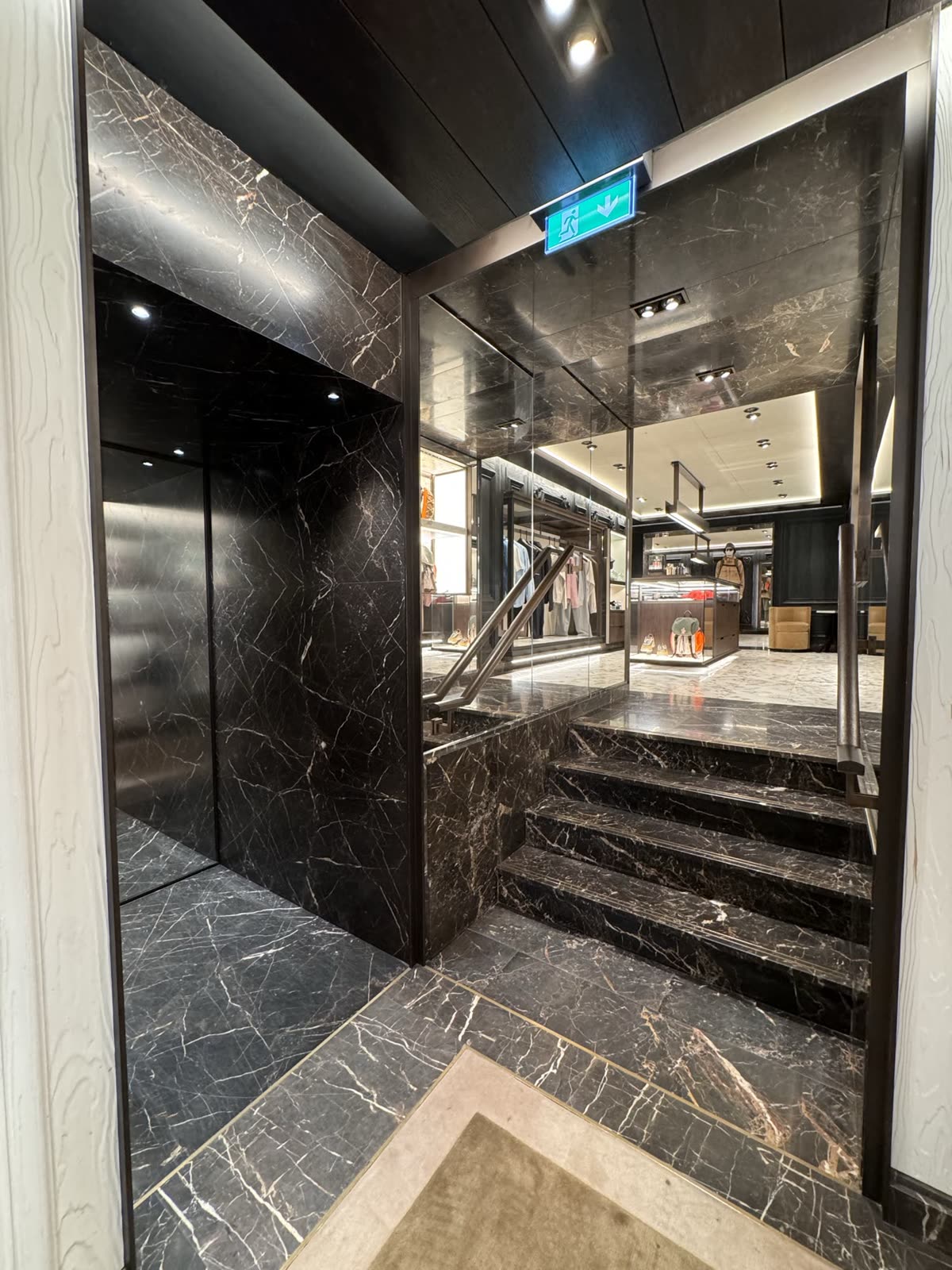 Dark marble stair and portal leading onto the shop floor, with a glazed balustrade — Moncler, London