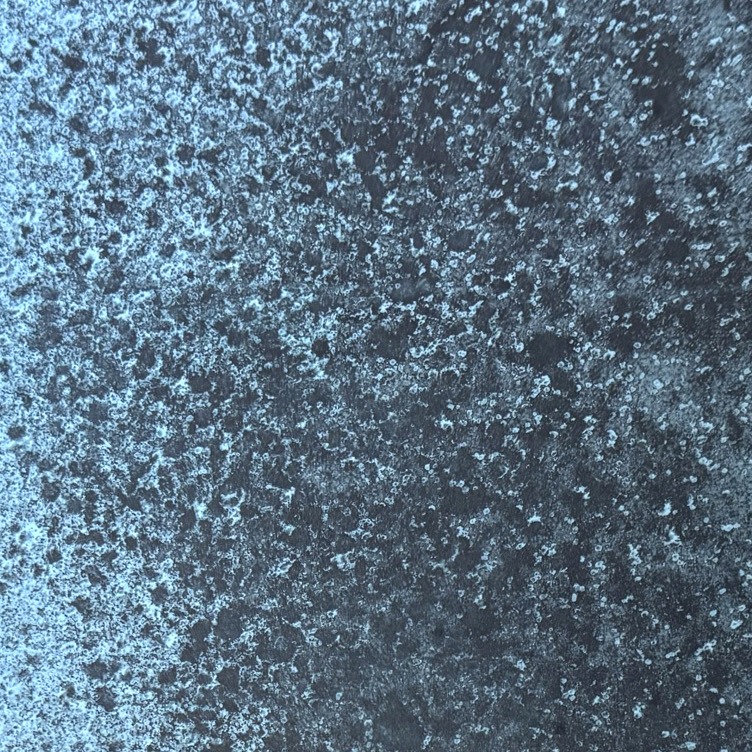 Close-up of an oxidised resin panel, pale mineral bloom spread across a dark blue ground