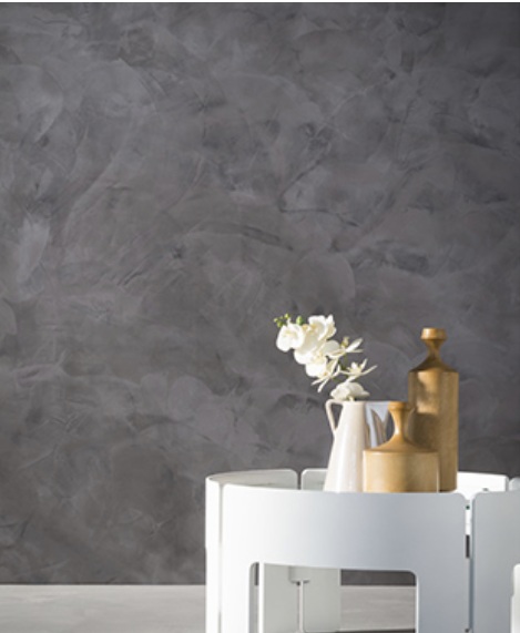 Graphite grey wall with cloud movement worked in by hand, behind a white side table with vases