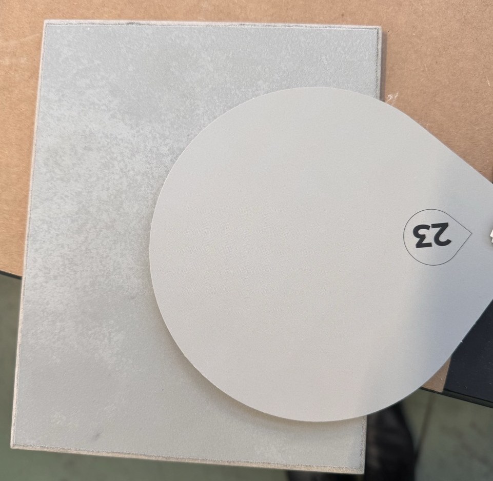 Hand-applied sample board on a workbench with a smooth numbered colour disc laid over it