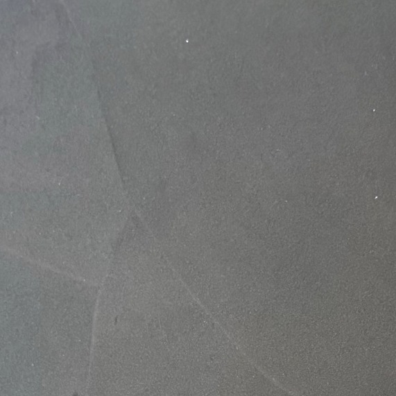 Close-up of a dark charcoal resin sample board with faint diagonal trowel lines