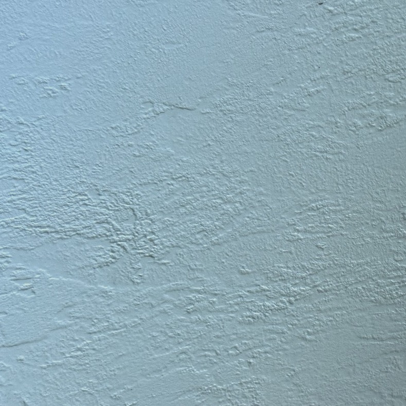Close-up of a pale blue resin sample board worked with a heavy, textured trowel pass