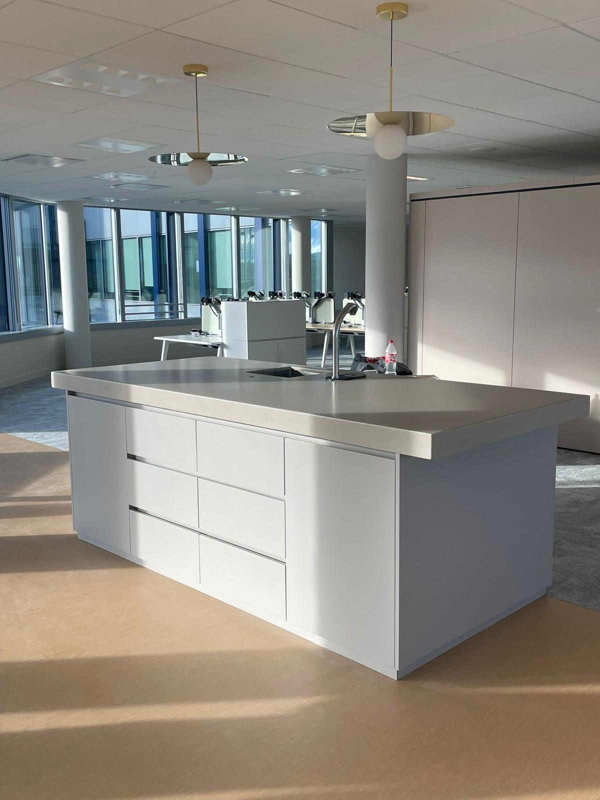 Resin worktop with a moulded upstand laid over white cabinetry, daylight raking across the finish